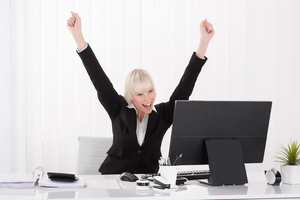 Happy Businesswoman Raising Arms At Desk Stock Image