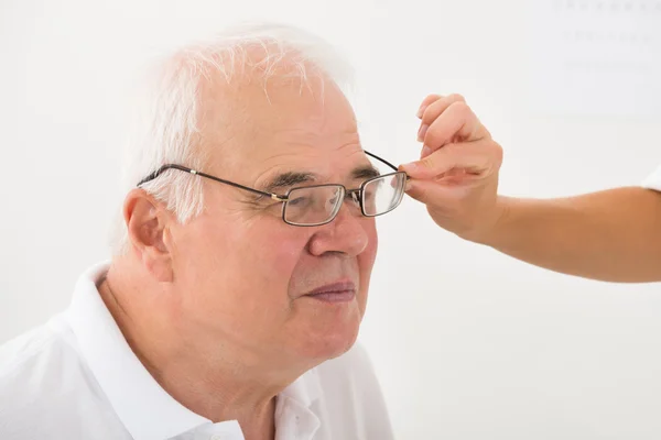 Un óptico ayudando a un paciente masculino con nuevas gafas —  Fotos de Stock