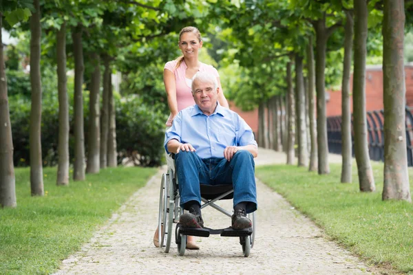 Mulher com seu velho pai sênior em cadeira de rodas — Fotografia de Stock