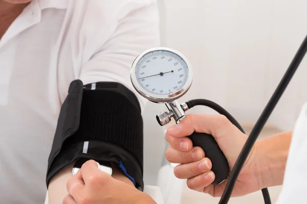 Médico verificando a pressão arterial do paciente — Fotografia de Stock