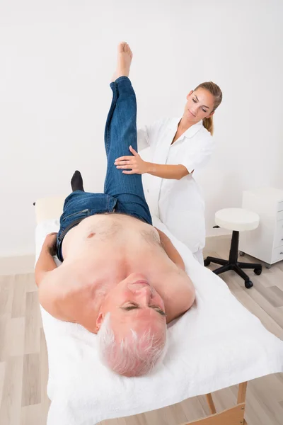 Massagista dando massagem na perna para o homem — Fotografia de Stock