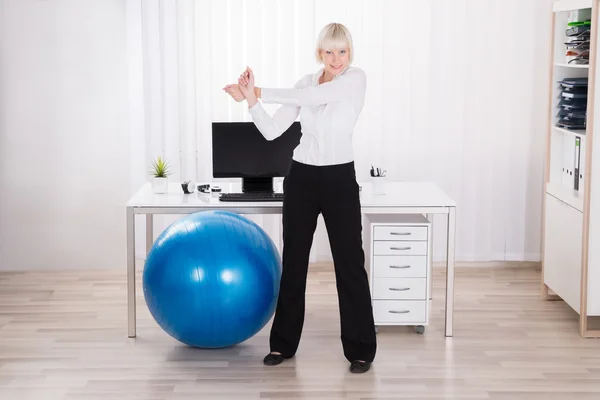 Empresária fazendo exercício no escritório — Fotografia de Stock