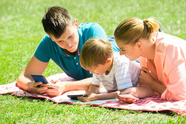 Family Laying Down In The Park With Their Smart Phones — Stock Photo, Image