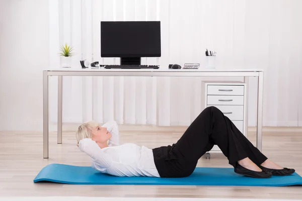 Empresária fazendo exercício no escritório — Fotografia de Stock