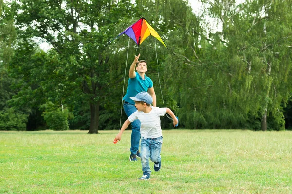 Vader lanceren van de Kite houden door zijn zoon — Stockfoto