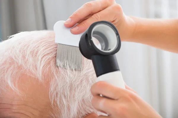 Arzt, der die Haare des Patienten behandelt — Stockfoto