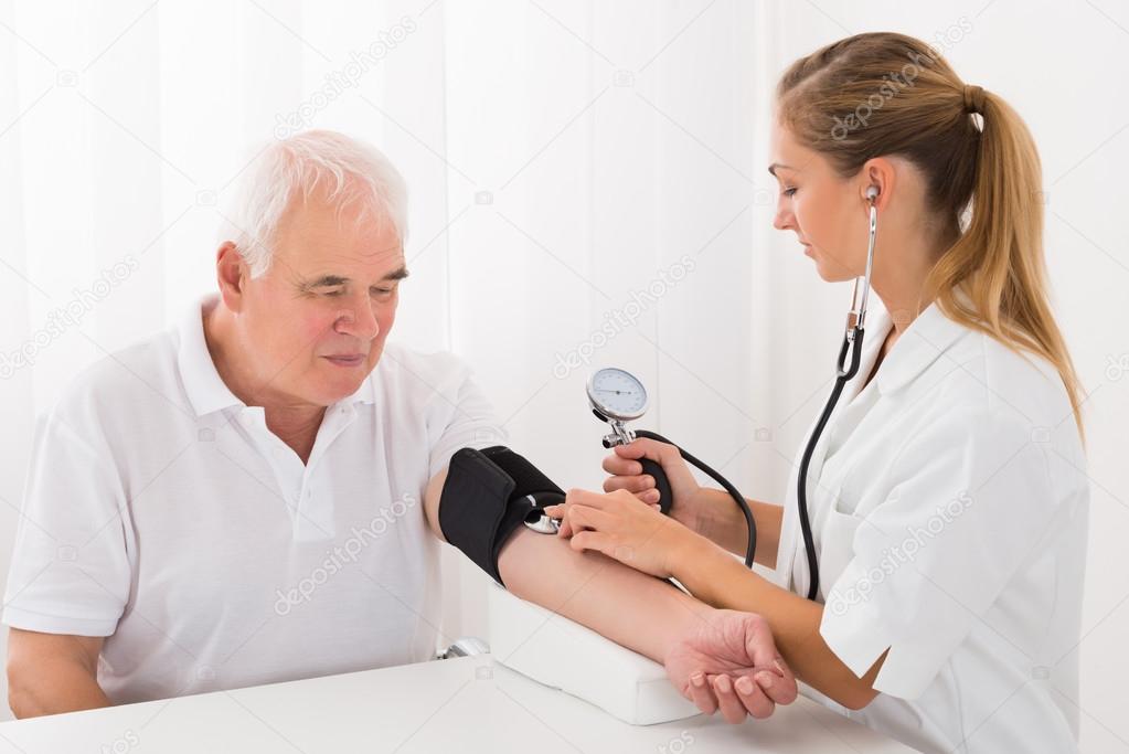 Female Doctor Checking Blood Pressure Of Male Patient