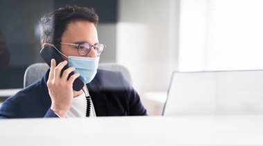 Ofisteki resepsiyonist yüz maskesi takıyor.