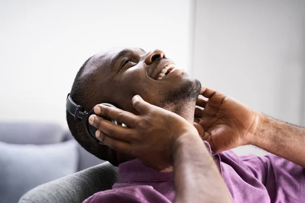 快乐的非裔美国人在家里通过耳机欣赏音乐 — 图库照片