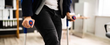 Ofiste Koltuk değnekleriyle duran engelli adam