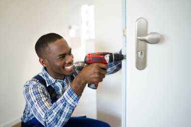 Afrikalı çilingir adam kapı kilidini değiştiriyor ve tamir ediyor