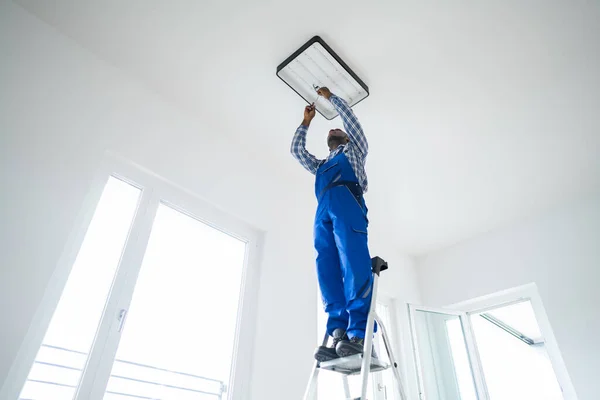 Africký Údržbář Elektrikář Žebříku Upevnění Instalace Světla — Stock fotografie