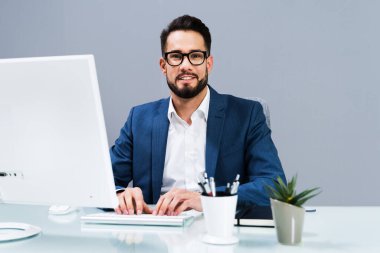 Masada iş bilgisayarında çalışan gülümseyen bir iş adamı