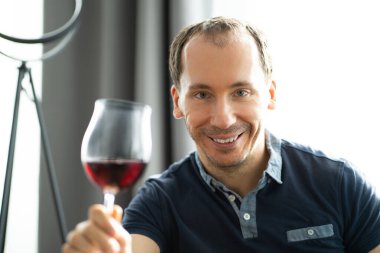 Evde video konferansında şarap içen adam.