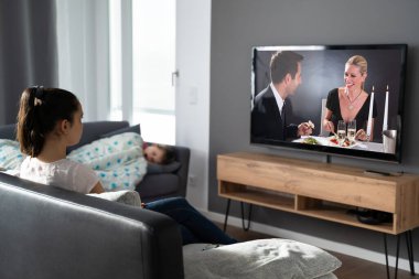 Çocuk uyurken TV seyreden bir kadın.