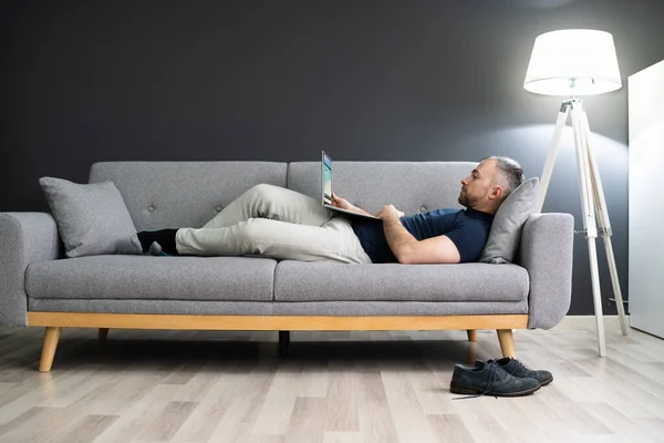 Homem Deitado Sofá Casa Usando Laptop — Fotografia de Stock