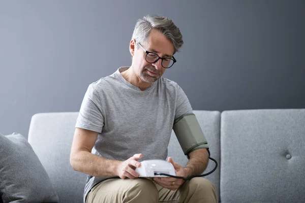 Elder Man Checking Blood Pressure At Home