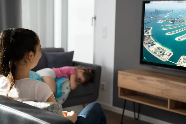 Frau Schaut Auf Sofa Fern Während Kind Schläft — Stockfoto