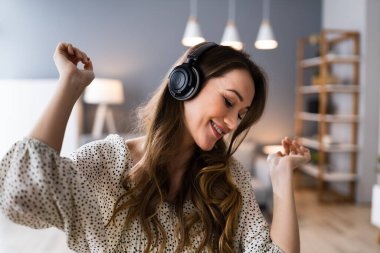 Gülümseyen Kadın Müzik dinliyor Oturma odasında kulaklık takıyor