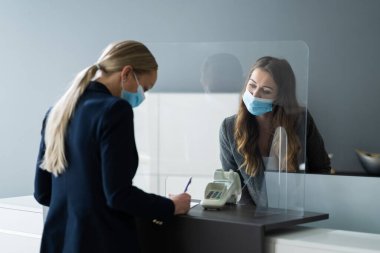 Otel resepsiyon masası tıbbi maske tarafından korunuyor.