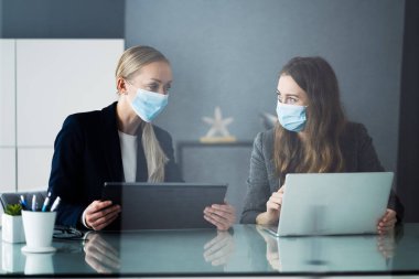 Ofis masasında maskeyle çalışan İş Analistleri