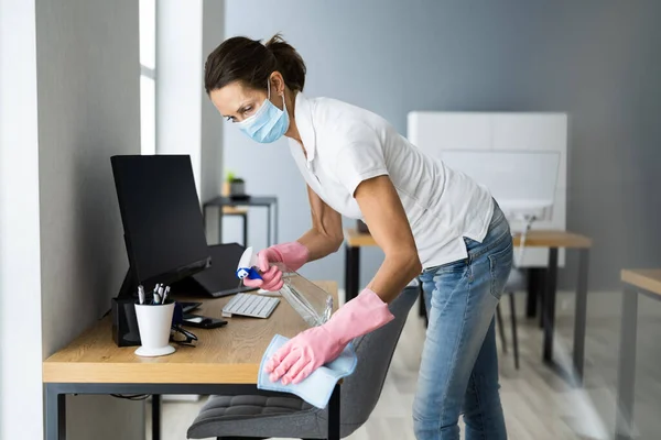 Office Desk Cleaning Service. Professional Janitor In Face Mask