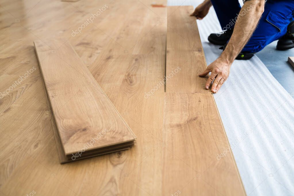 Worker Installing Home Floor. Carpenter Laying Laminate Flooring