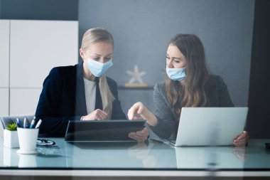 Ofis masasında maskeyle çalışan İş Analistleri