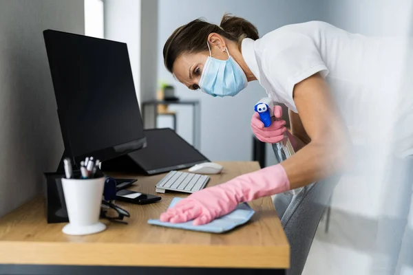 Office Desk Cleaning Service. Professional Janitor In Face Mask