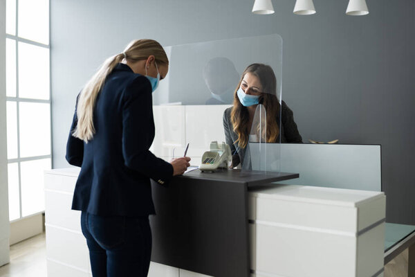 Стойка регистрации отеля защищена медицинской маской от Covid 19