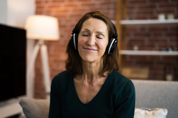 リビングルームでヘッドフォンを使用して音楽を聴く笑顔の女性 — ストック写真