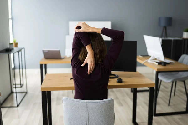 オフィスのデスクで運動を伸ばす 仕事中の女 — ストック写真