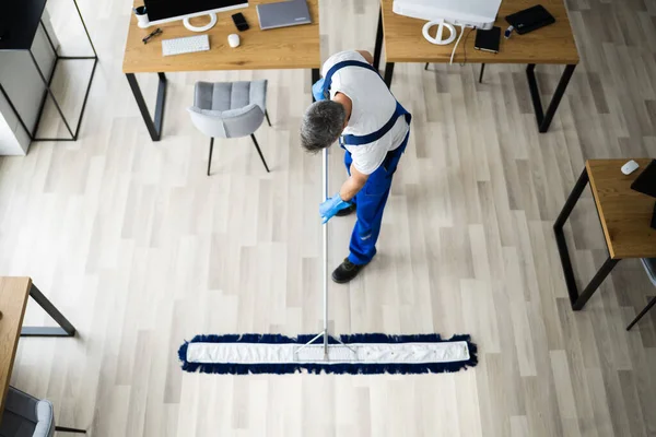 Αρσενικός Επιστάτης Σφουγγαρίζοντας Πάτωμα Στη Μάσκα Προσώπου Στο Γραφείο — Φωτογραφία Αρχείου