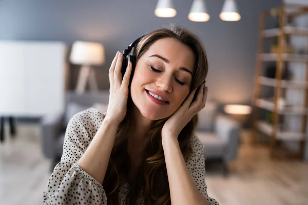 Uśmiechnięta Kobieta Słuchanie Muzyki Pomocą Słuchawek Salonie — Zdjęcie stockowe