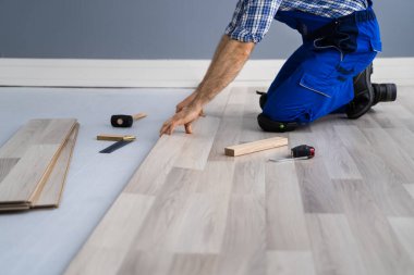 Ahşap döşeme tadilatı. İnşaat işçisi yeni Laminate kurulumunu yapıyor