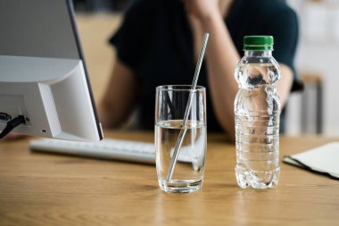 Ön planda Kadın ve Masada Bardak İçmek Bilgisayar Kullanmak