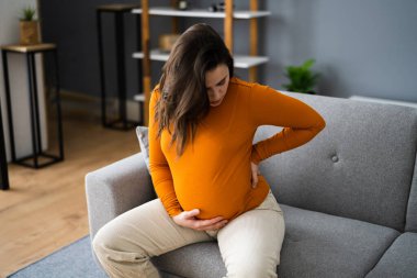 Sırtı ağrıyan ve sırt ağrısı olan hamile kadın.