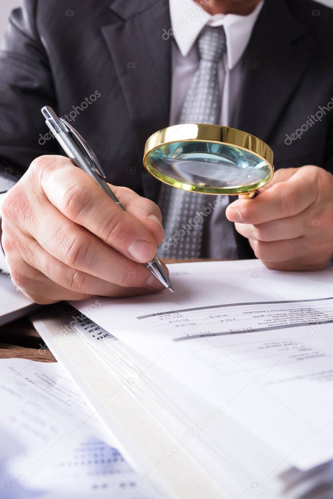 Auditor Using Magnifying Glass For Audit And Fraud Investigation