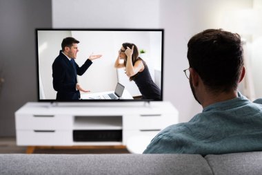 Oturma odasında kanepede TV filmi izliyorum.