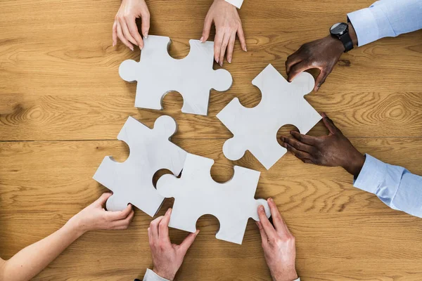 Teamwork Meeting Hands Solving Jigsaw Puzzle At Desk