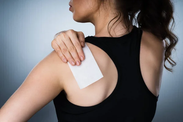 Woman Applying Stiff Shoulder Pain Patch After Injury