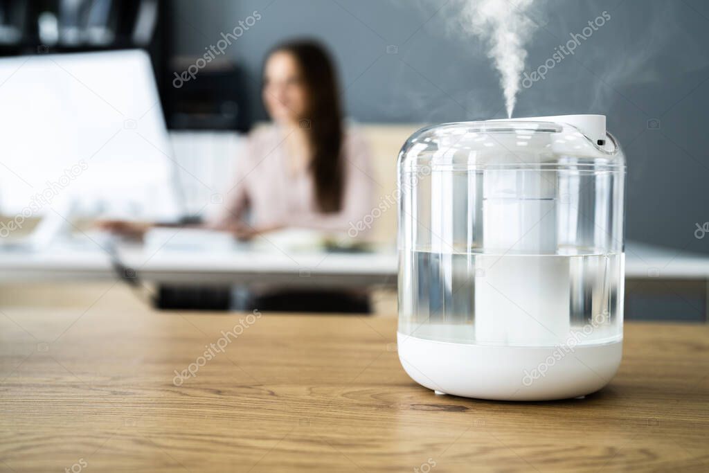 Air Humidifier Device At Office Desk Near Woman Working