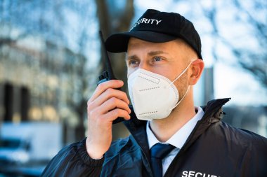 Security Officer In FFP2 Covid Mask Using Walkie Talkie clipart