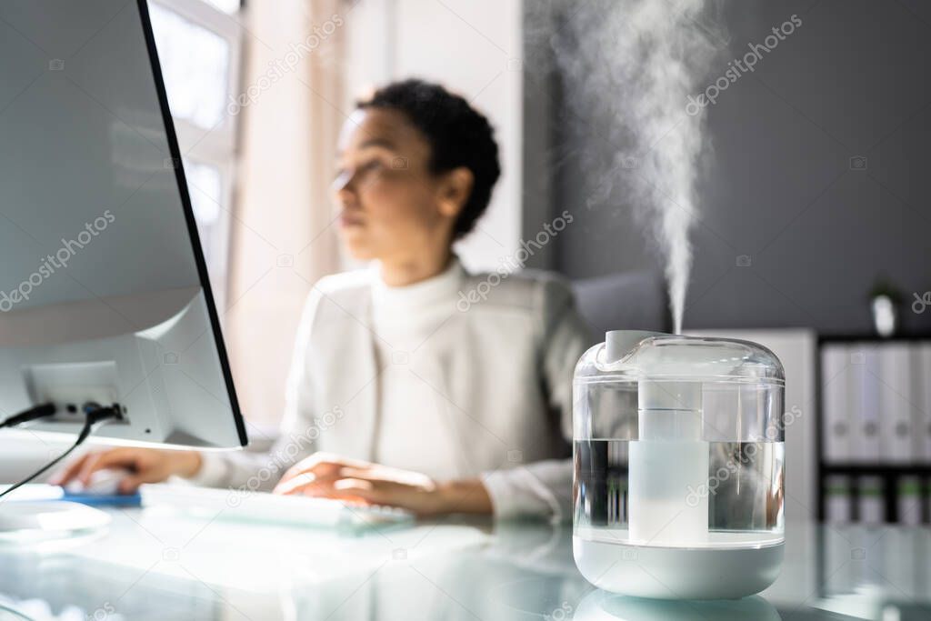 African American Woman In Office With Air Humidifier
