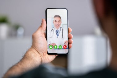Evde doktorla görüntülü konuşma yapan bir adam.