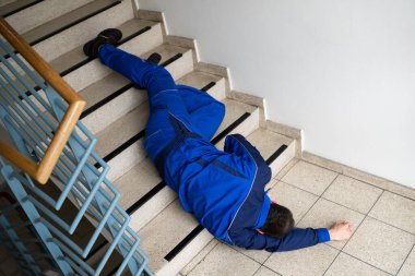 Düştükten ve düştükten sonra merdivenlerde yatan işçi.