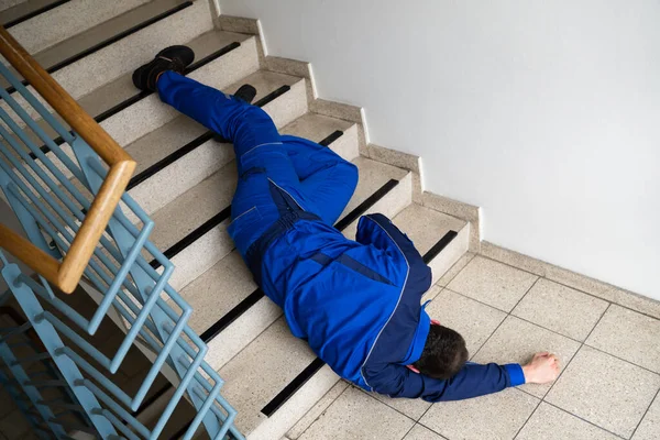 スリップした後 階段に横たわる労働者の男と秋の事故 — ストック写真