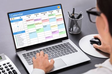 Yönetici bilgisayardaki takvime bakıyor. Haftalık Zamanlama Ayarlanıyor