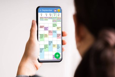 Yönetici cep telefonundaki takvime bakıyor. Haftalık Zamanlama Ayarlanıyor
