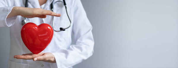 Доктор со стетоскопом, держащим сердце. Концепция кардиологического страхования